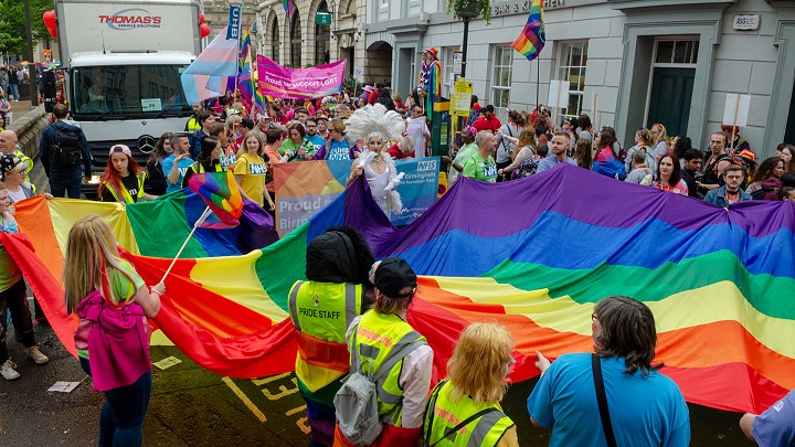 Man in a shiny pink suit on stilts smiles for the camera